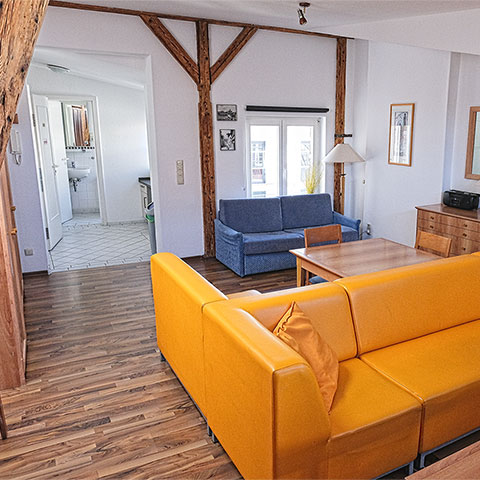 Hiddensee Loft — Schlafbereich mit historischen Holzbalken und Boxspring-Bett